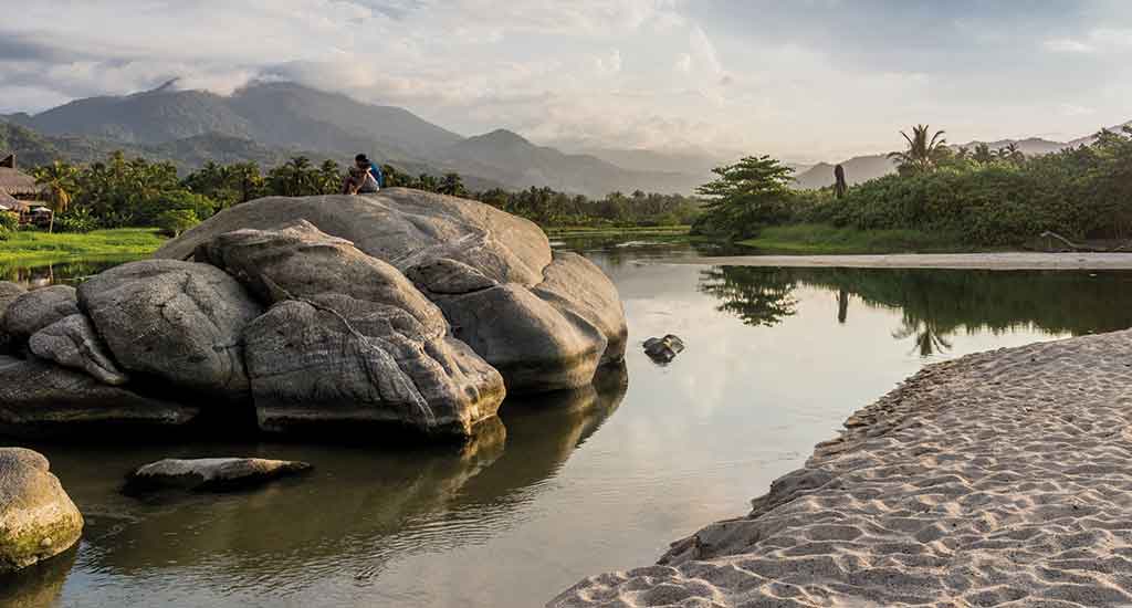 A man on top of a boulder in Los Naranjos beach
