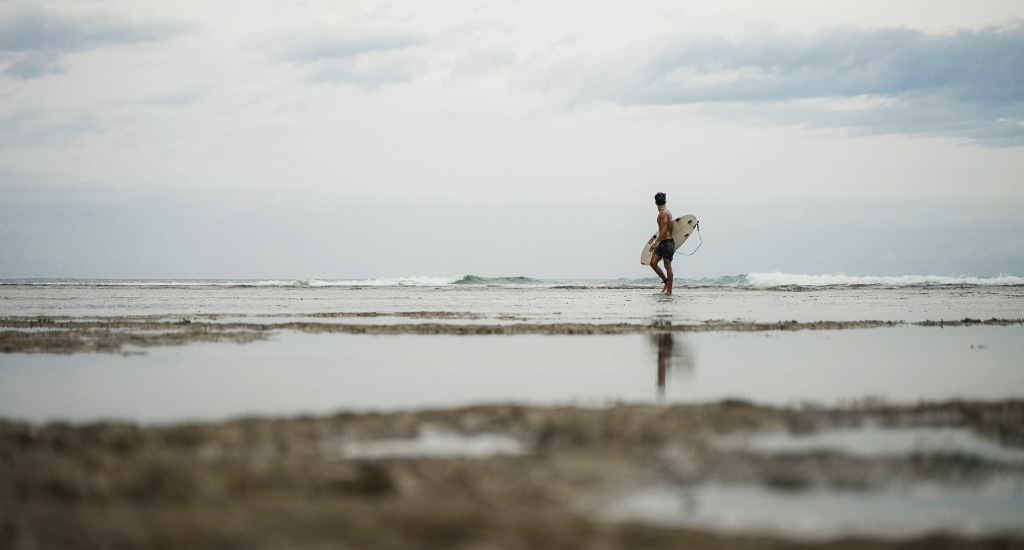 Man carrying surfboard in a beach in Siargao